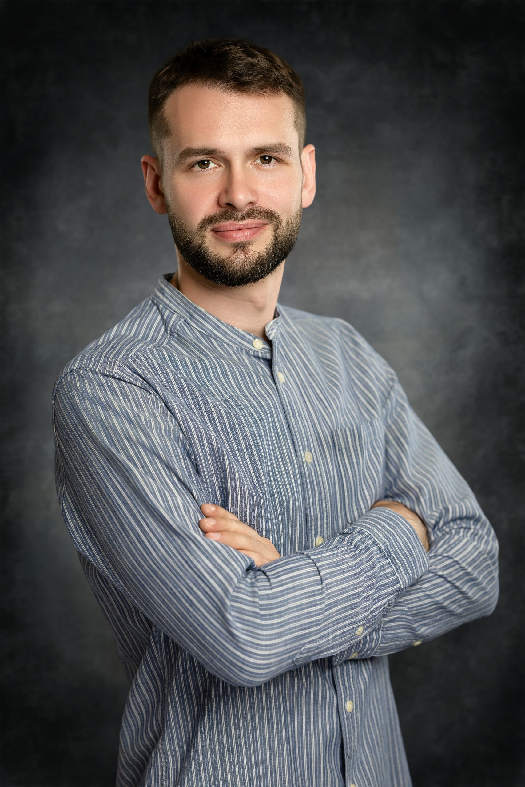 April_25_2026_21_27_22_Vlad_Mixer_Austin_Texas_Photographer Professional corporate headshot of a man with arms crossed on a uniform textured backdrop